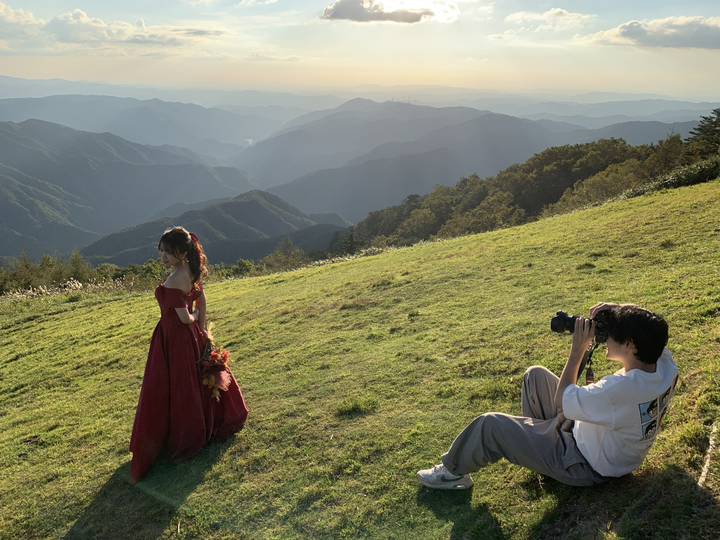 山の上の草原で花嫁を撮影するカメラマン