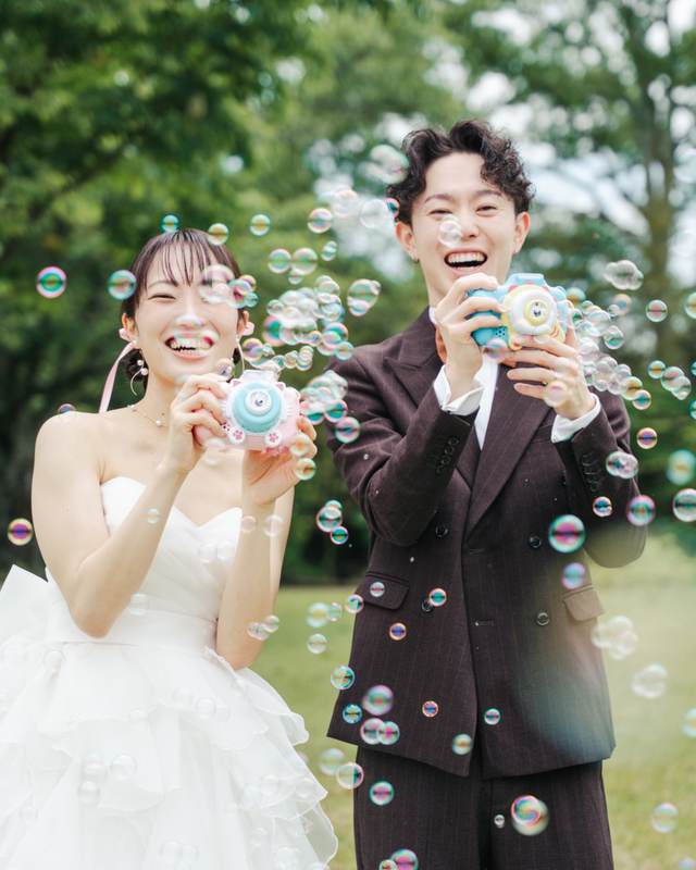 シャボン玉のなかで笑い合うドレスとスーツの二人