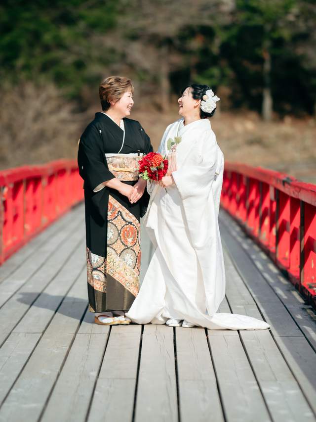 赤い橋の上で笑い合う白無垢の花嫁